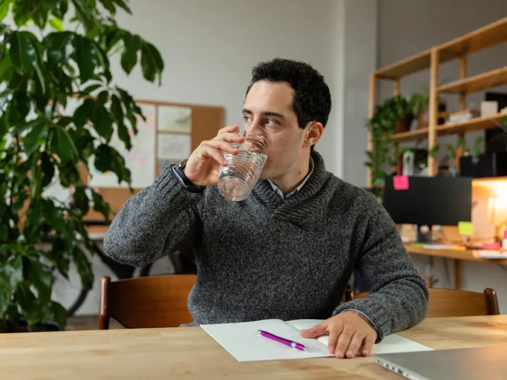 A person takes a sip of water, focusing on hydration and well-being.
