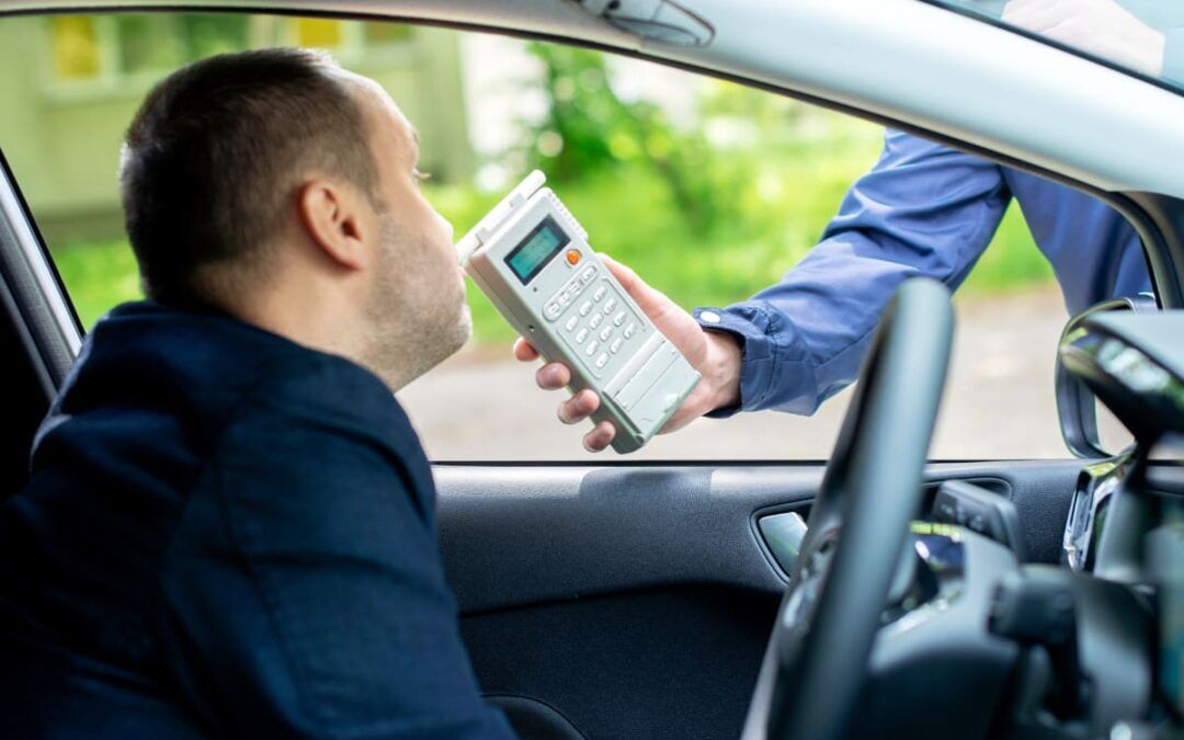 A police officer uses a breathalyzer on a driver.