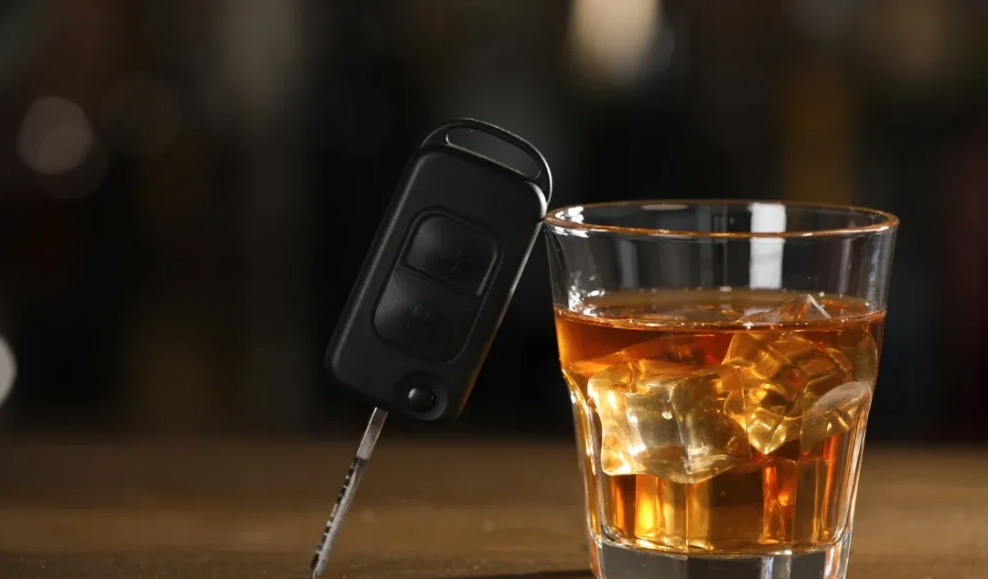 A glass of alcohol next to a car key