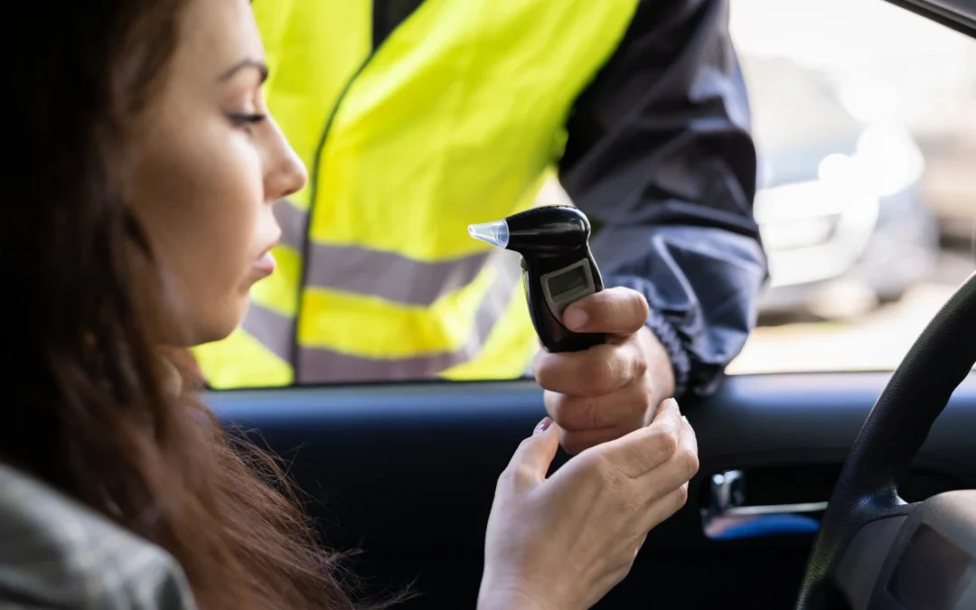 A police officer conducts a sobriety test on a driver using a breathalyzer.